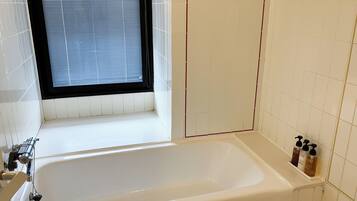 Een bad/douchecombinatie, een haardroger, handdoeken, zeep