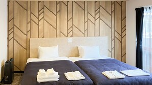 A hotel room with two beds, a wooden patterned wall, and a window with curtains. - HOTEL LiVEMAX Naha Naminoue II (Naha)