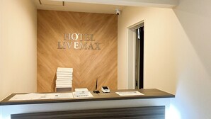 A hotel reception desk with a wooden panel wall displaying the name 'HOTEL LIVEMAX'. - HOTEL LiVEMAX Naha Naminoue II (Naha)