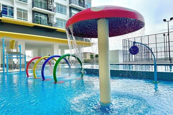 A swimming pool with a water feature shaped like a mushroom, surrounded by colorful rings.