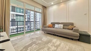 A modern living room with a sofa, a coffee table, and a large window with a view of a building. - Melaka Novo 8 Residence - Jonker Street by Stayrene (Melaka)