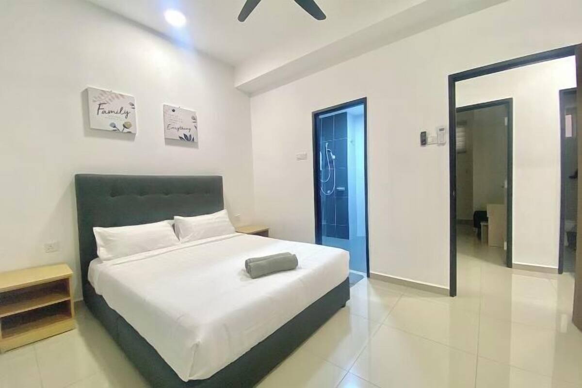 Quarto moderno com uma cama grande, uma mesa de cabeceira e uma porta para o banheiro.