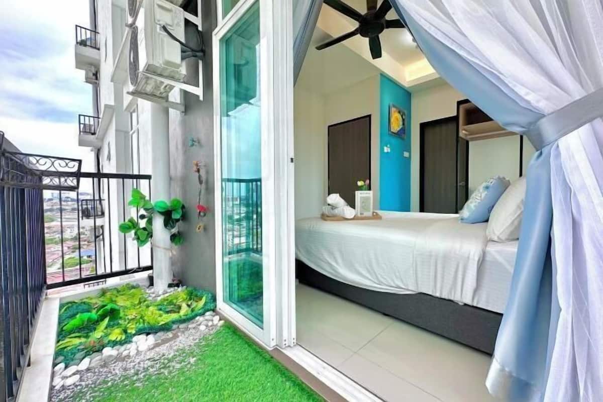 Quarto com cama, janela e varanda com plantas.