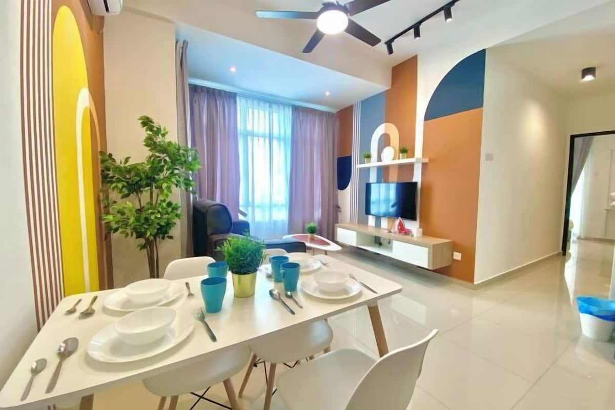 Uma sala de jantar moderna com uma mesa posta para quatro pessoas, um ventilador de teto e uma televisão na parede.