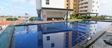 A rooftop pool with clear blue water, surrounded by modern buildings.