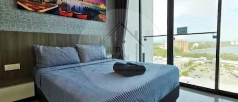 A modern bedroom with a large bed, a cityscape view, and a painting on the wall.