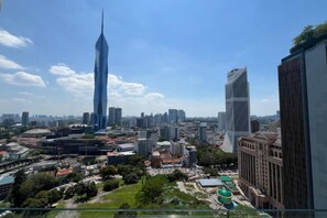 Un paysage urbain avec des gratte-ciel modernes, un ciel dégagé et un mélange d’espaces urbains et de zones vertes.
