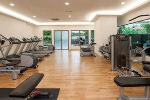 Een fitnessruimte met loopbanden, elliptische trainers en gewichten.