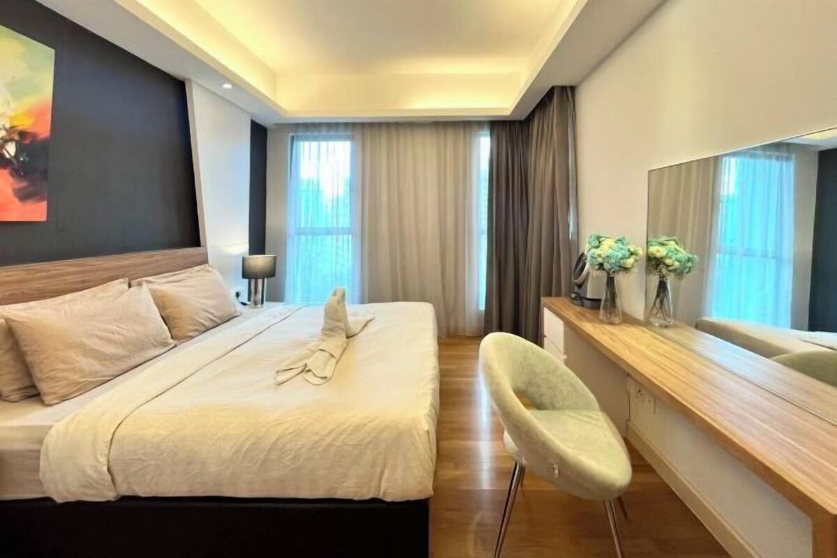 Une chambre d’hôtel moderne équipée d’un lit, d’une table de chevet, d’une chaise et d’un grand miroir.