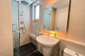 Une salle de bain avec une douche à parois de verre, un lavabo blanc et un miroir au-dessus.