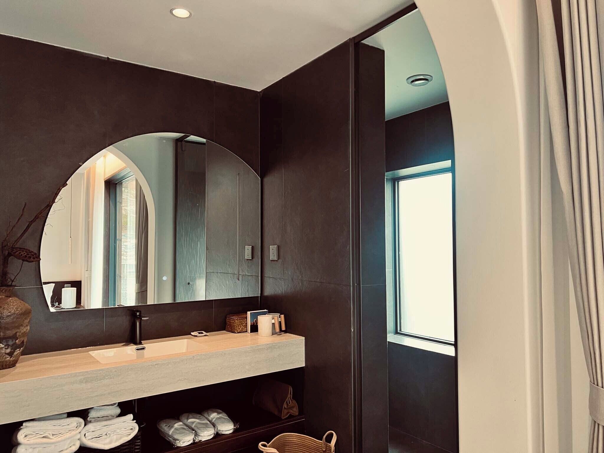 Une salle de bain moderne avec un grand miroir, un lavabo et une fenêtre.