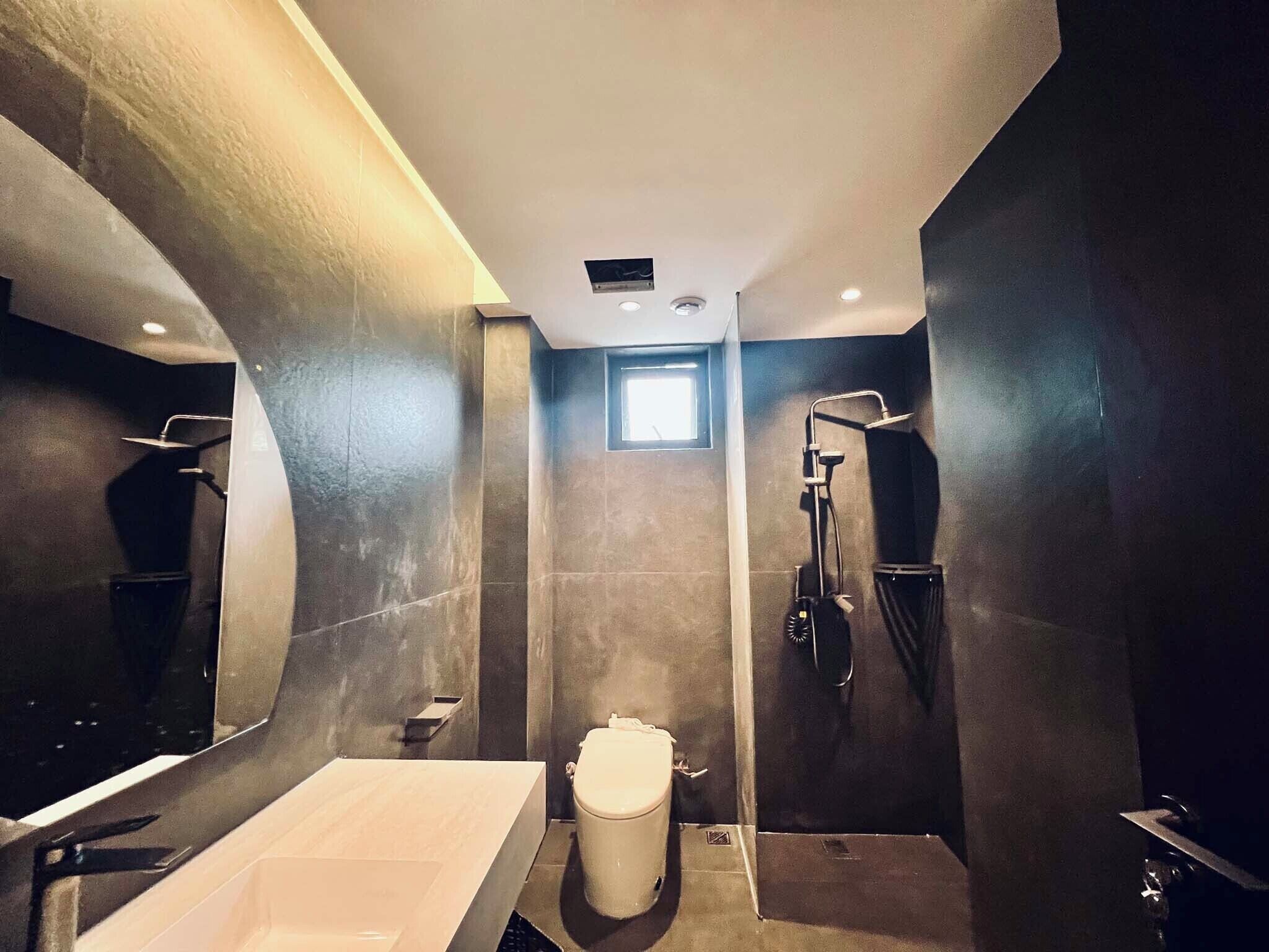 Un baño moderno con un espejo grande, una bañera, un inodoro y una ducha.