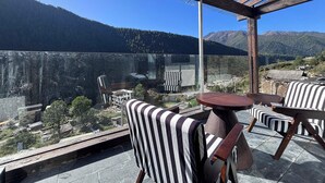 A terrace with a view of a lake and mountains, featuring striped chairs and a round table. - Mid Hill White Lodge (Ngawa Autonomous Prefecture)