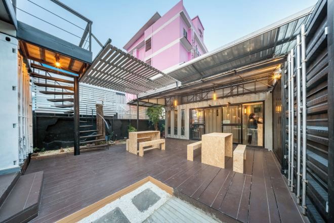 Un espace extérieur aménagé en terrasse, avec un sol en bois, une pergola et des sièges.