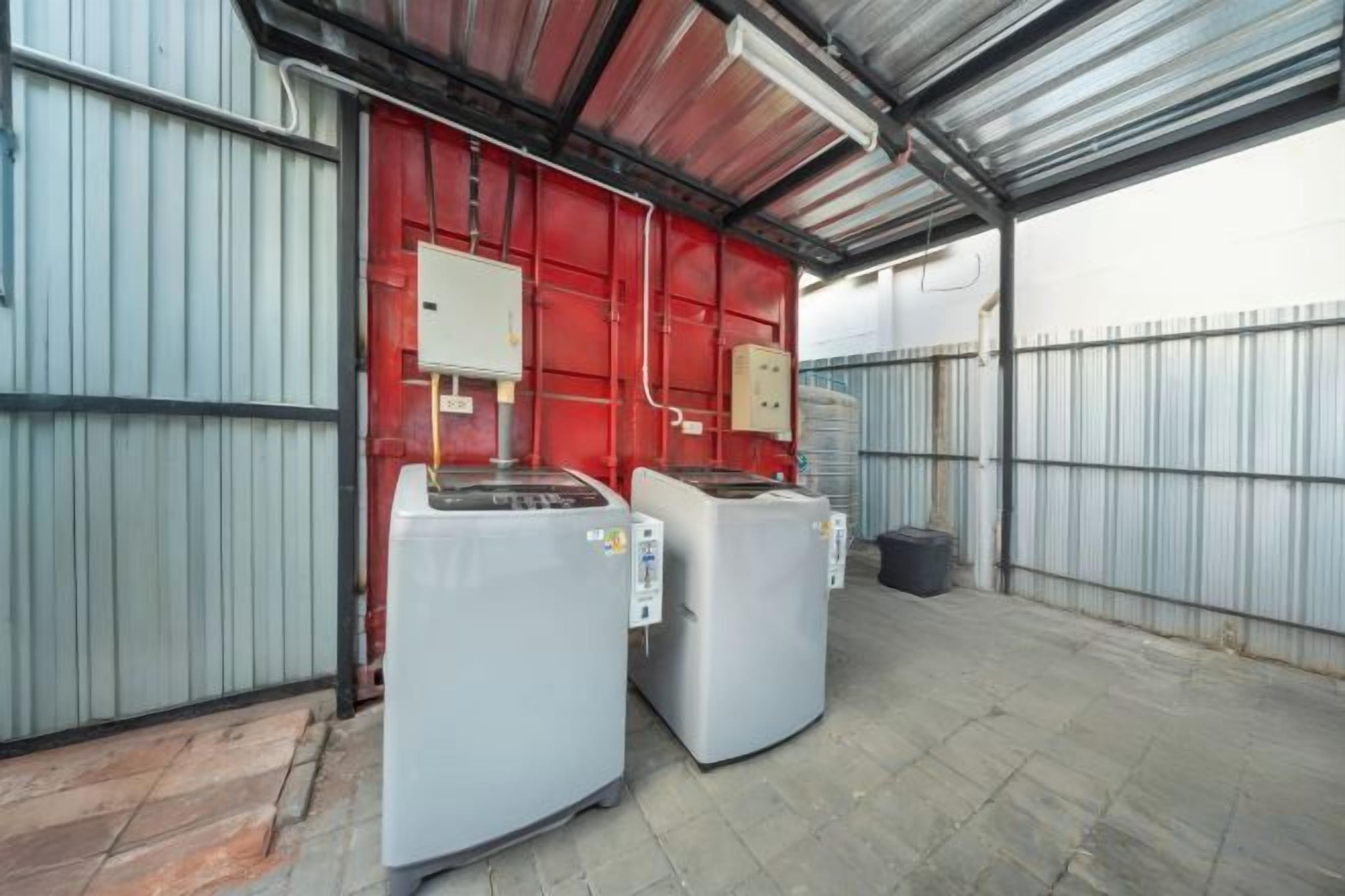 A large industrial space with two large white machines, a red door, and a metal fence.