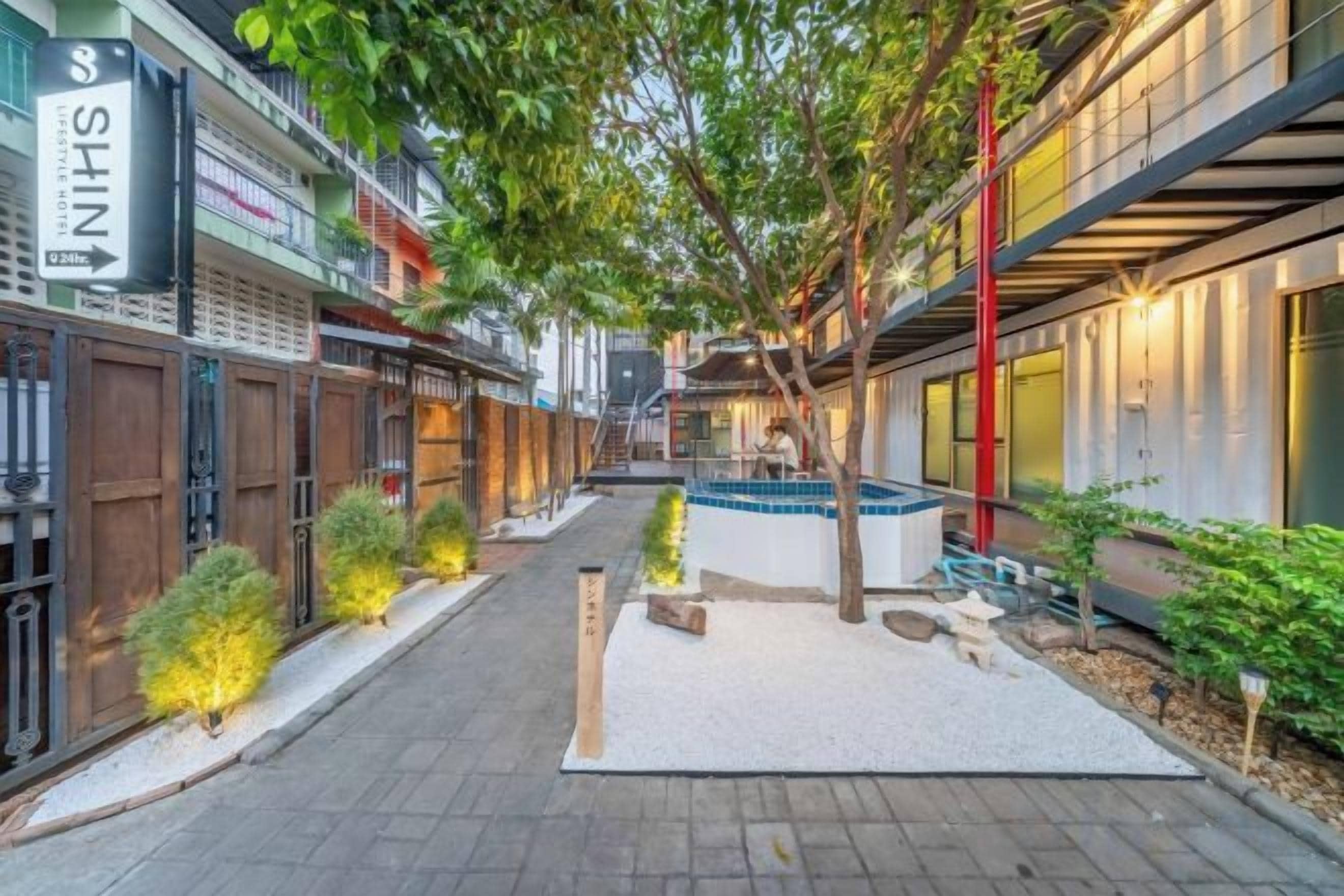 An outdoor corridor with a pathway, wooden fences, and a small seating area with a table and chairs.