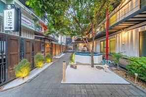 Un pasillo exterior con un sendero, vallas de madera y una pequeña zona de estar con una mesa y sillas.