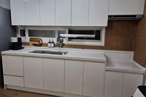 Una cocina moderna con armarios blancos, microondas integrado y encimera de madera.