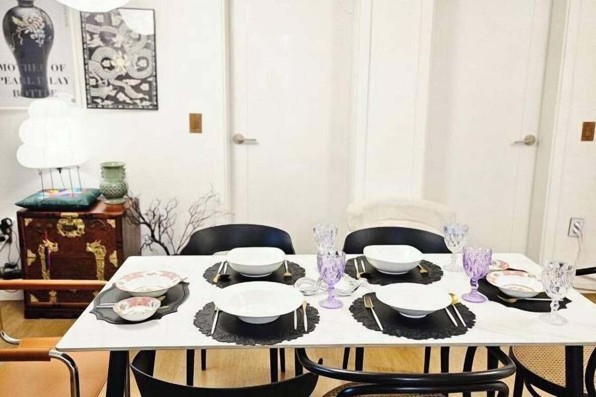 Una mesa de comedor dispuesta con platos, cubiertos y vasos, rodeada de sillas.