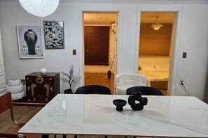 A dining area with a marble table, chairs, a cabinet, and artwork on the wall. - 8 minutes away from Chungmuro Station, hill location,Breakfast for more than five nights (Seoul)