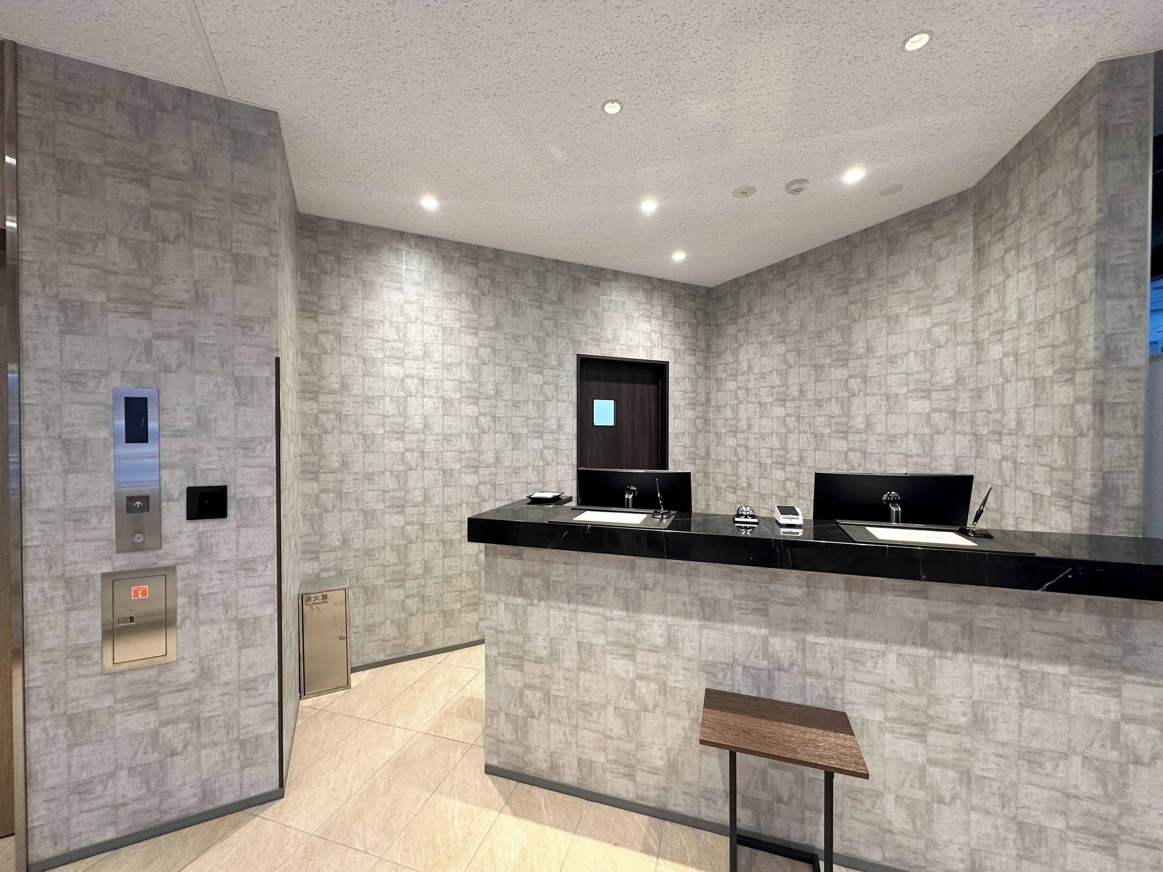 A modern bathroom with a black countertop, two sinks, a mirror, and a small stool.
