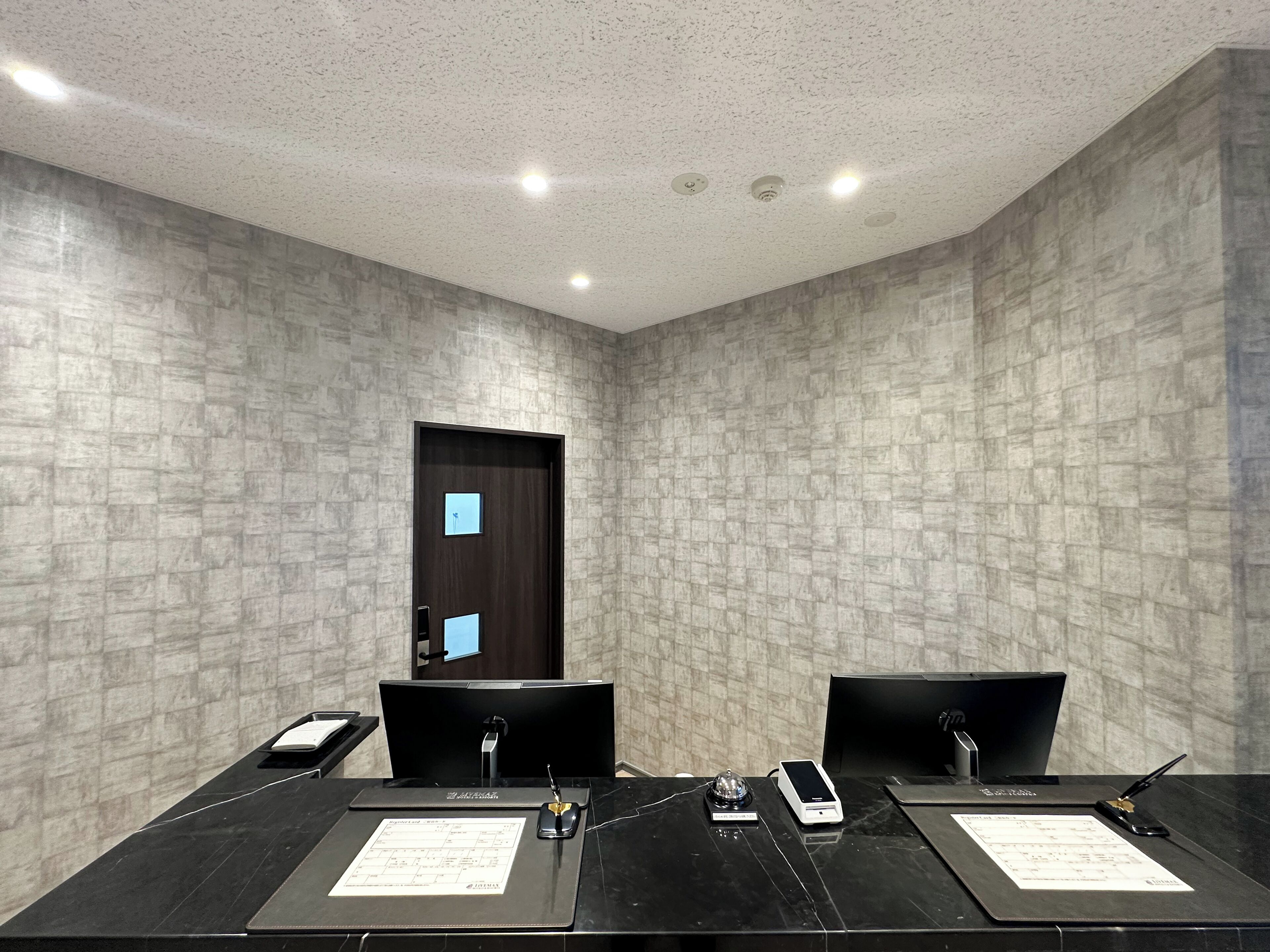 Un salón de conferencias con una mesa de mármol, sillas negras y una puerta con interruptor de luz.