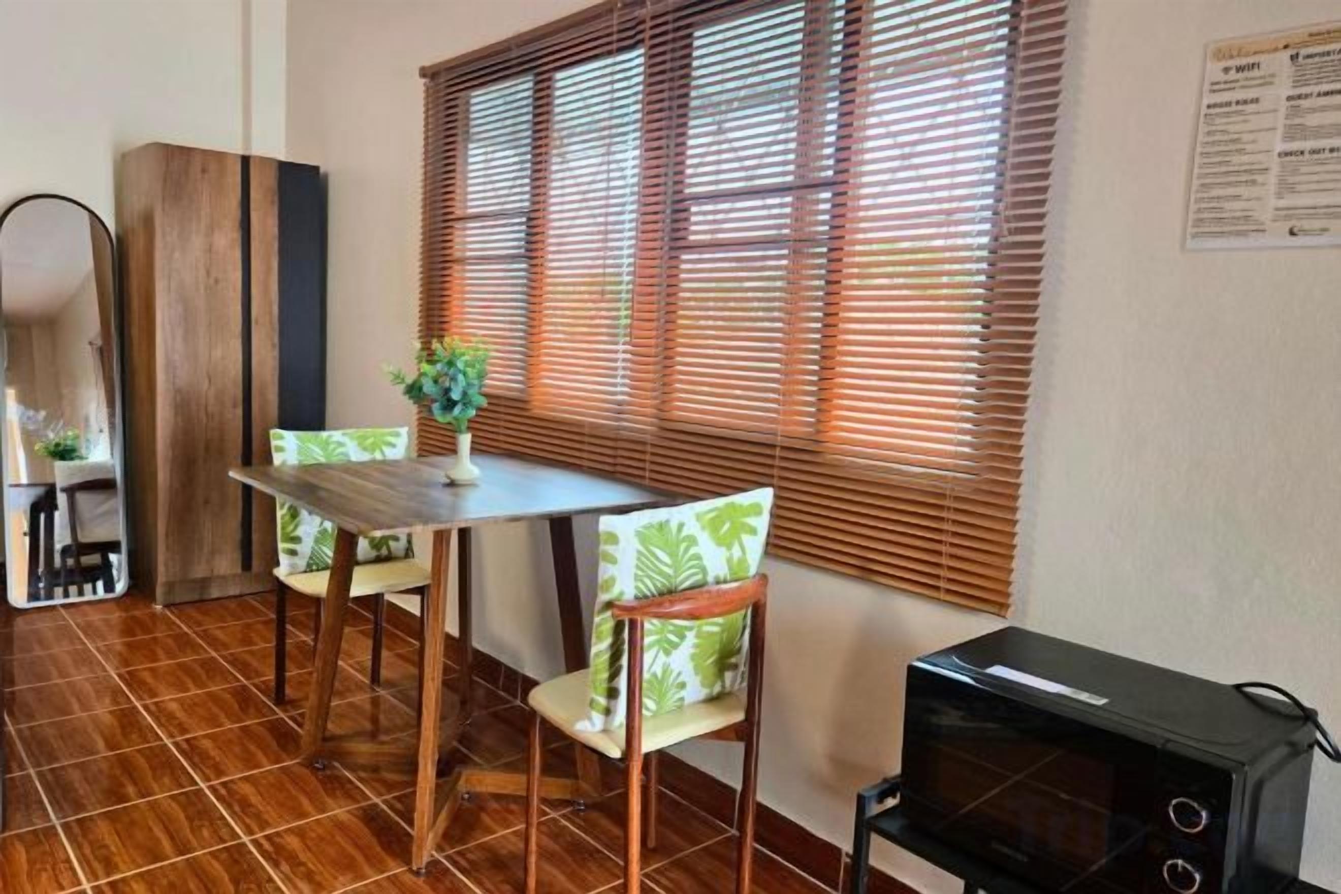 A dining area with a table and chairs, a microwave, and a window with blinds.