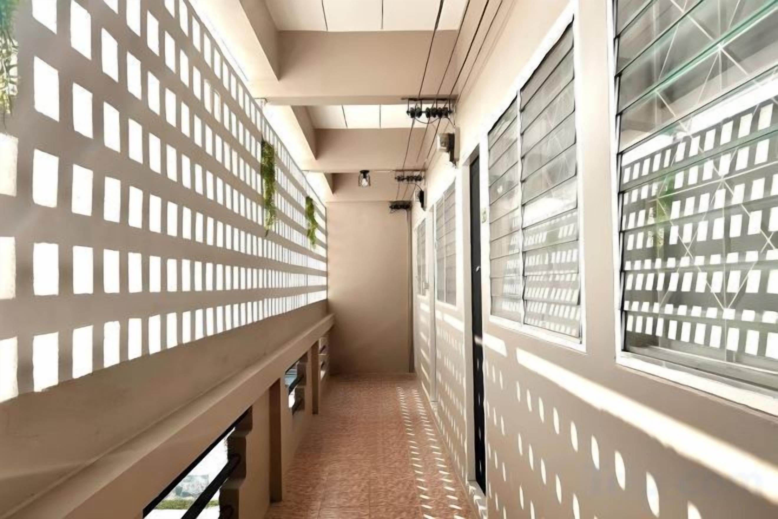 A corridor with patterned walls and windows, leading to a room with a view.