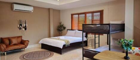A hotel room with a bed, a sofa, a desk, and a window with blinds.