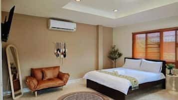 A bedroom with a bed, a leather sofa, a mirror, and a window with blinds.