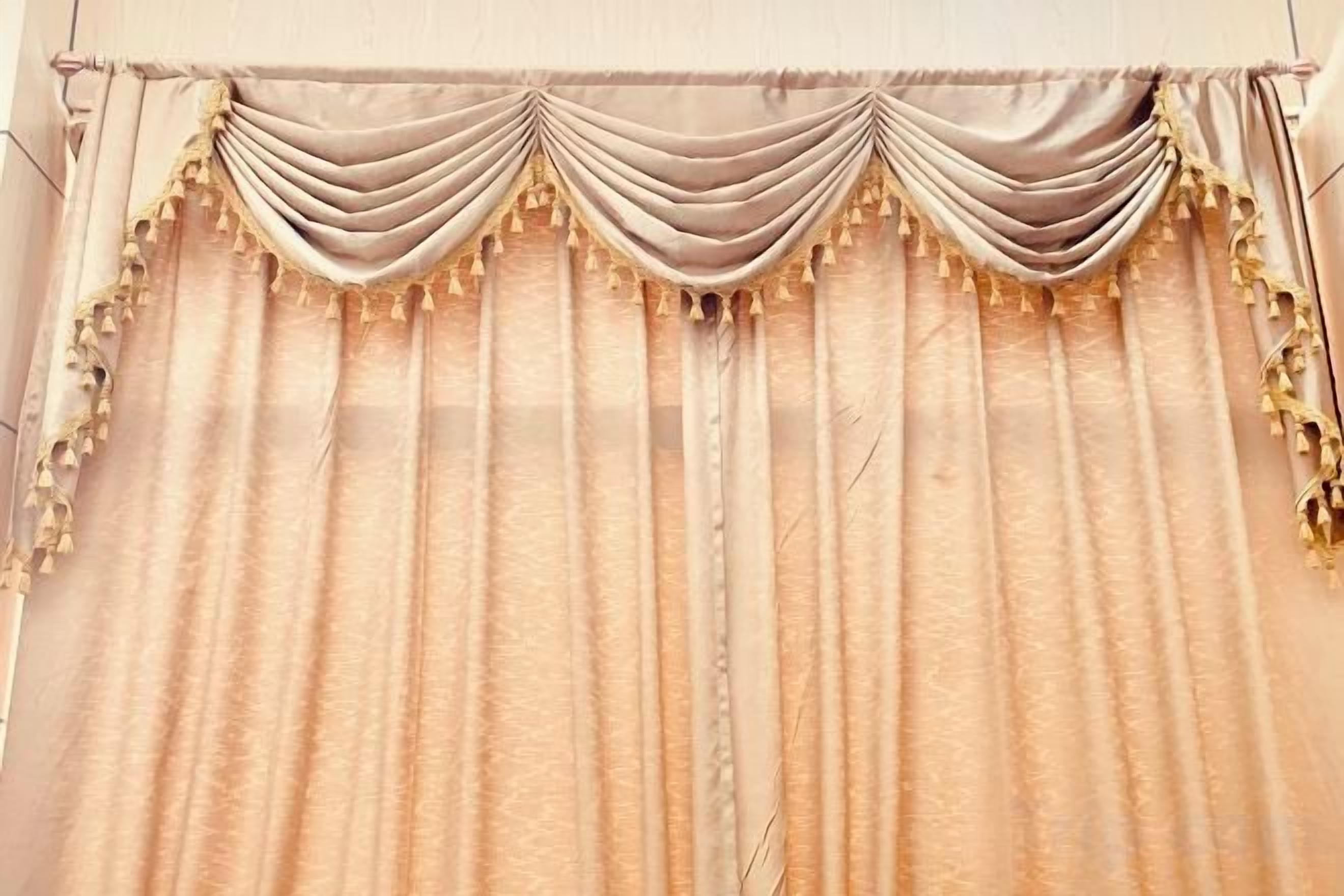Una ventana con cortinas drapeadas y un canasto decorativo.