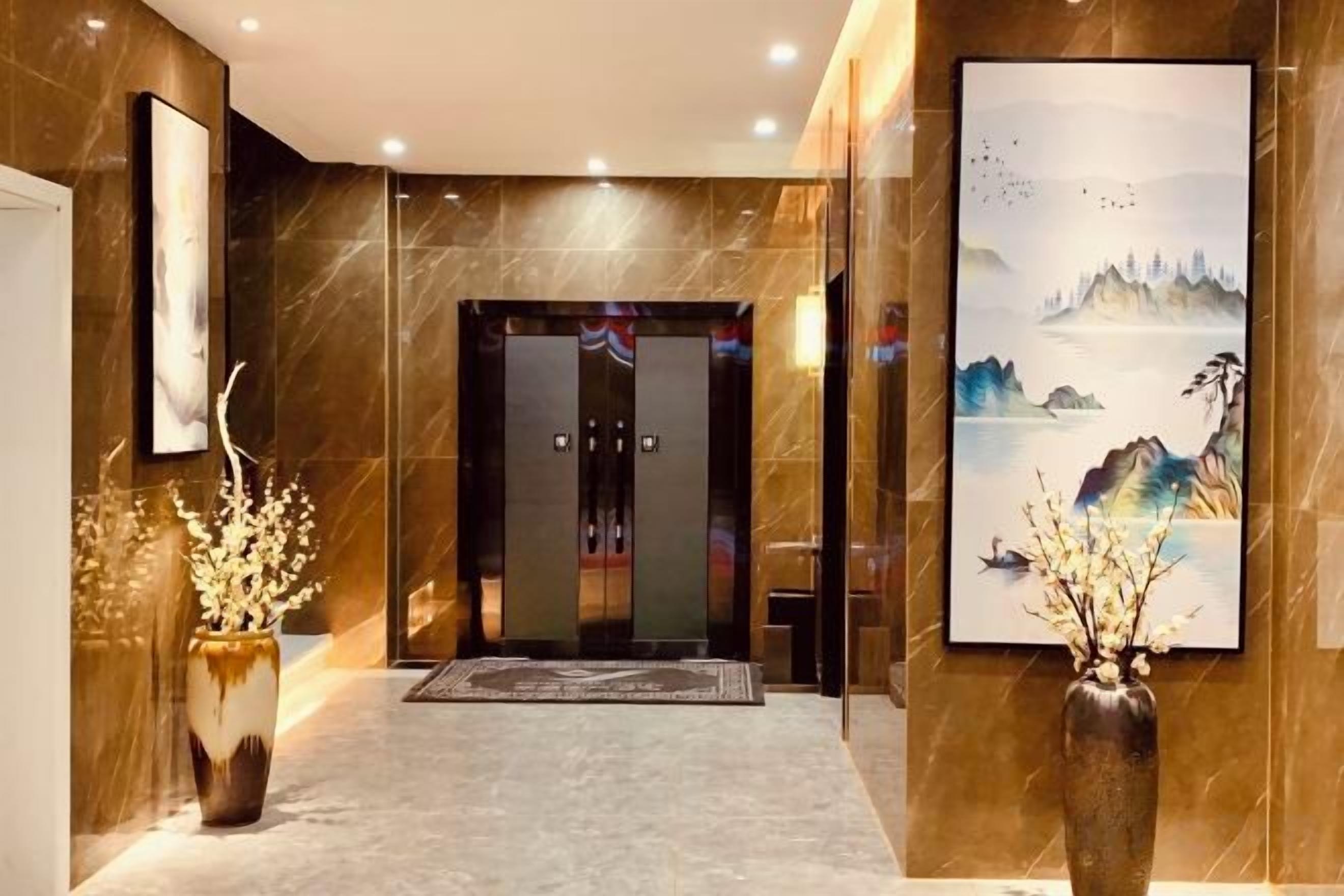 A hotel lobby with a reception desk, a large painting, and a vase with flowers.