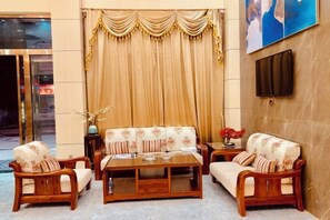 A hotel lobby with a sofa set, wooden coffee table, and a TV mounted on the wall. - Youngsun Hotel (Sihanoukville)