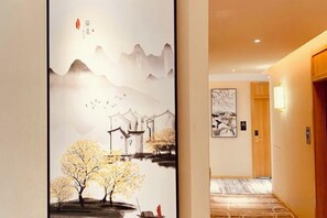 A hallway with traditional artwork on the walls, a carpeted floor, and a wooden door. - Youngsun Hotel (Sihanoukville)