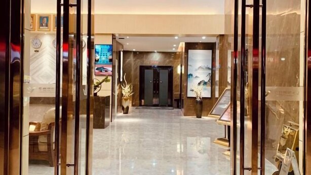 A hotel lobby with a marble floor, a reception desk, and a wall-mounted TV. - Youngsun Hotel (Sihanoukville)