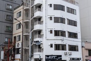 A multi-story building with balconies, a sign for 'LPT' on the ground floor, and a fire hydrant on the sidewalk. - Kaike shibaura (Tokyo)