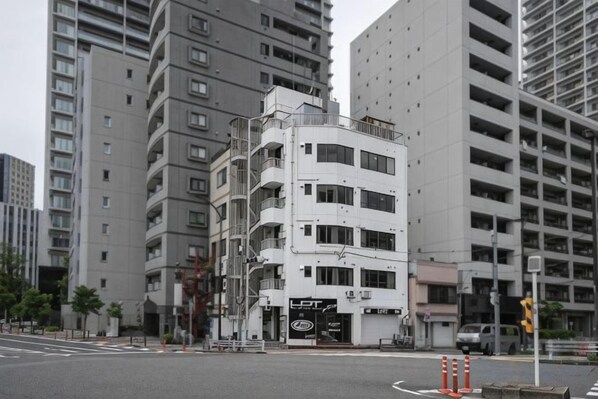 A multi-story building with a commercial ground floor, surrounded by taller residential buildings.