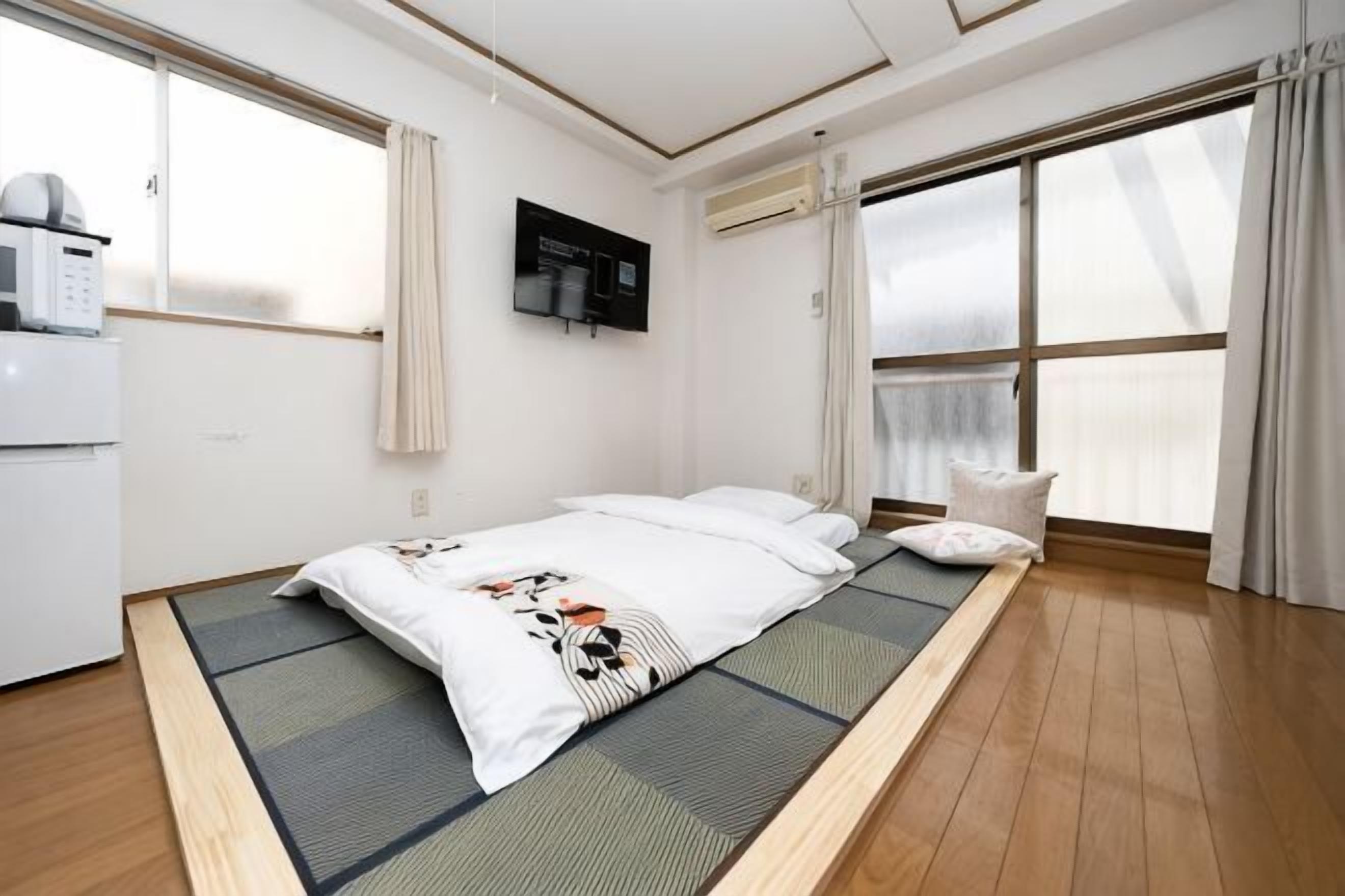 Ein Zimmer mit einem Bett, einer kleinen Küchenzeile und einem großen Fenster.