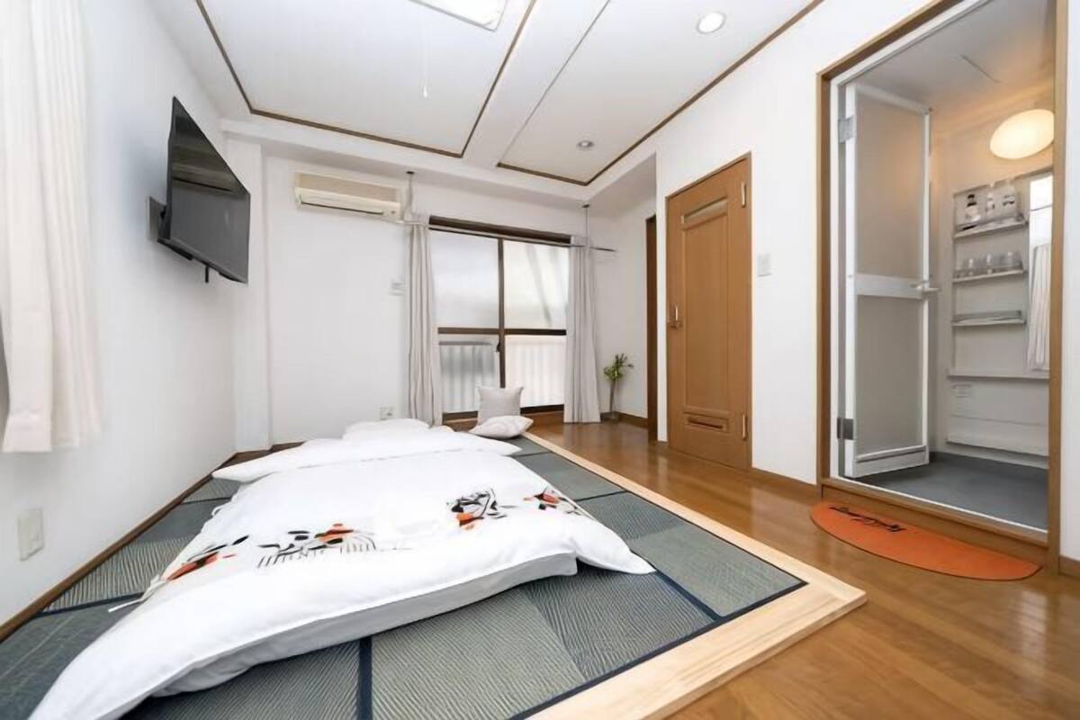 A room with tatami mats, a bed, a TV, a sliding door, and a closet.