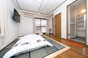 A room with tatami mats, a bed, a TV, a sliding door, and a closet.