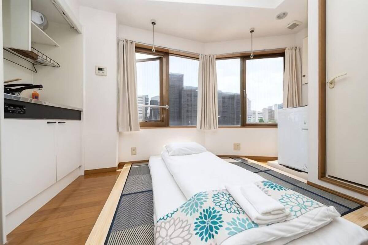 Quarto de hotel com cama, cozinha compacta e vista para a cidade.
