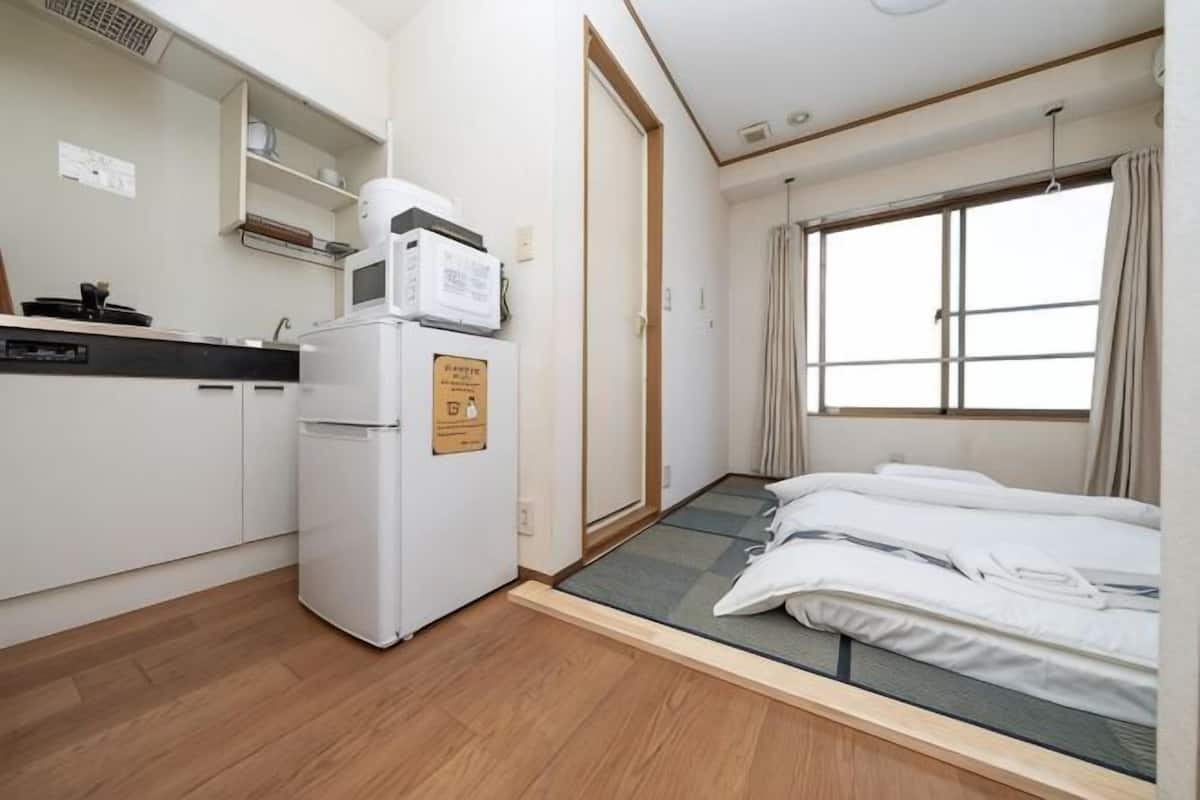 Ein kleines Zimmer mit Küchenzeile, einem Bett und einem Fenster.