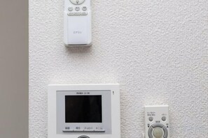 A wall-mounted thermostat and a control panel with a screen and buttons. - Kaike shibaura (Tokyo)