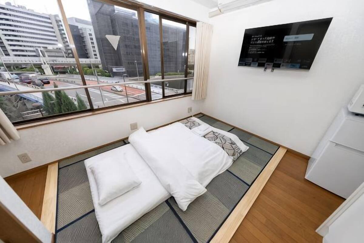 A room with a bed, a view of the city, and a mounted TV.