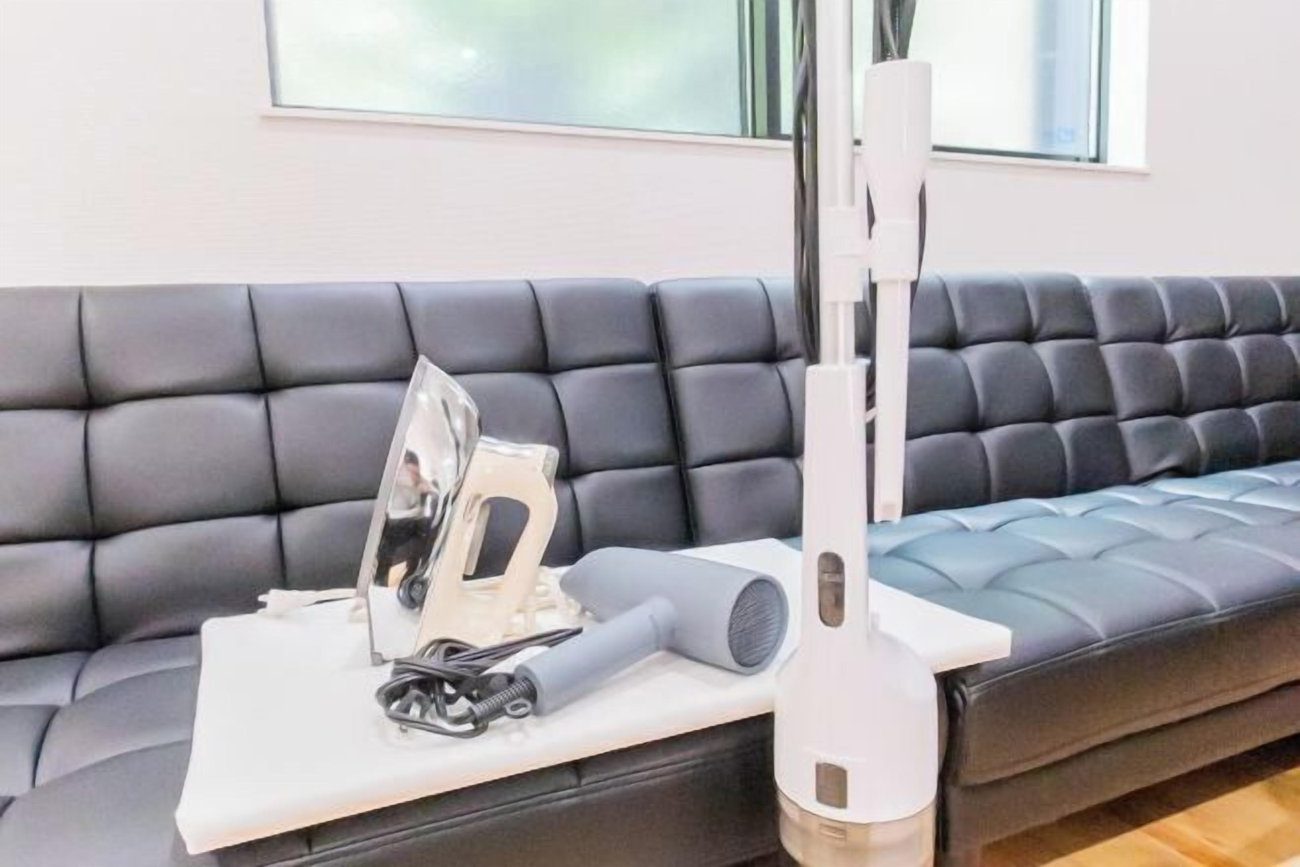 A modern living room with a black leather sofa, a white coffee table, and a white standing lamp.