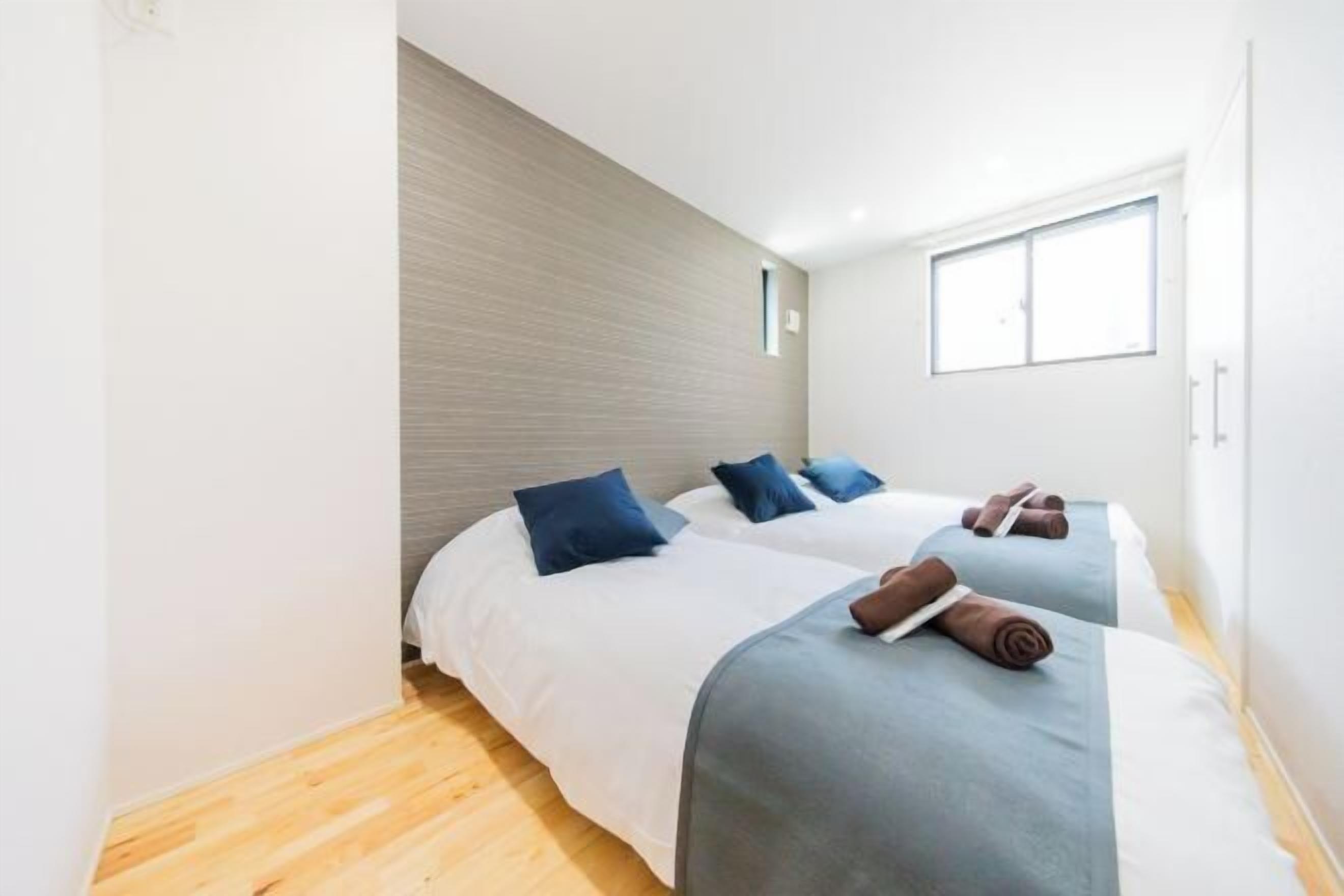 A hotel room with two beds, a window, and a wooden floor.
