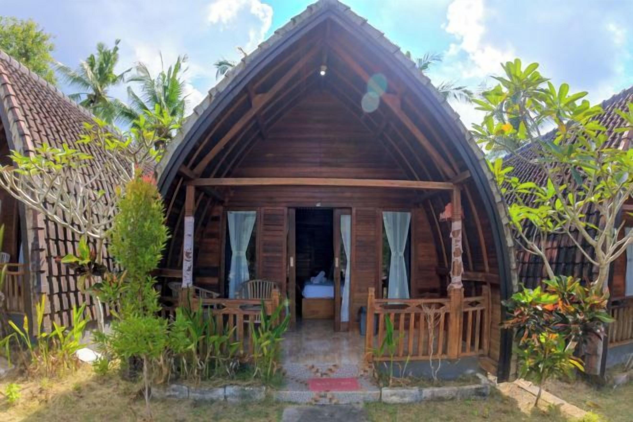 A wooden cabin with a porch, a bed, and a small table.