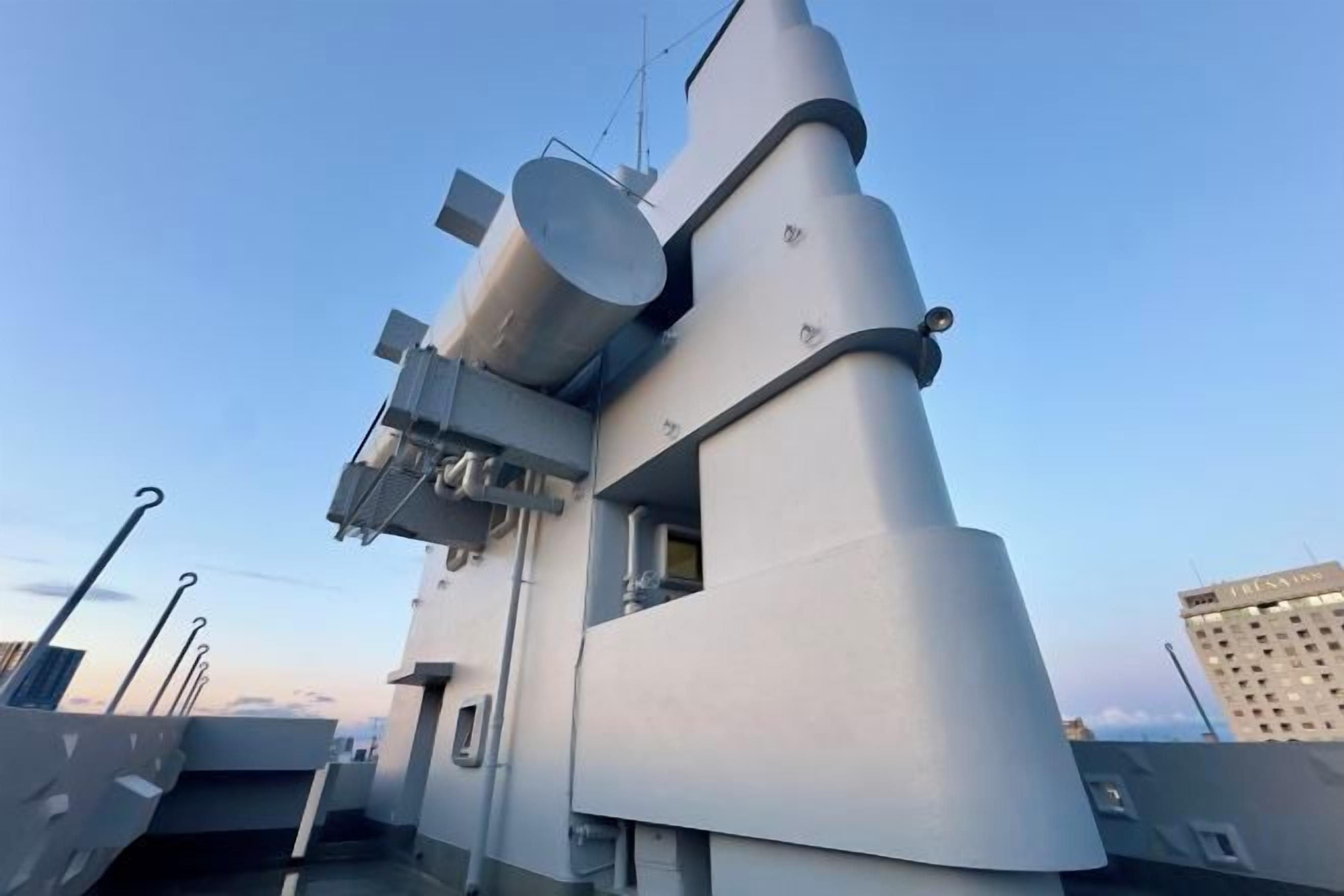 A ship's deck with a large gun turret, radar equipment, and a bridge structure.