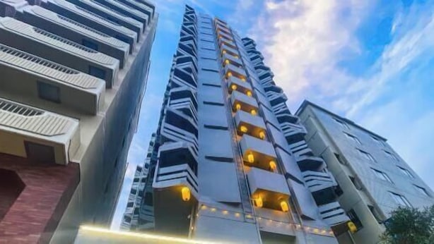 Un edificio alto con varios balcones, diseño arquitectónico moderno y cielo despejado al fondo.