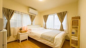Un dormitorio con cama, mesita de noche, lámpara y una pequeña estantería.